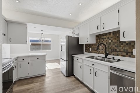 A modern kitchen with white cabinets and a tiled backsplash.