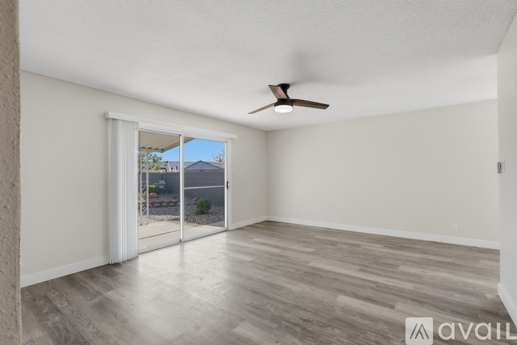 A room with a ceiling fan and sliding glass doors leading to a patio.
