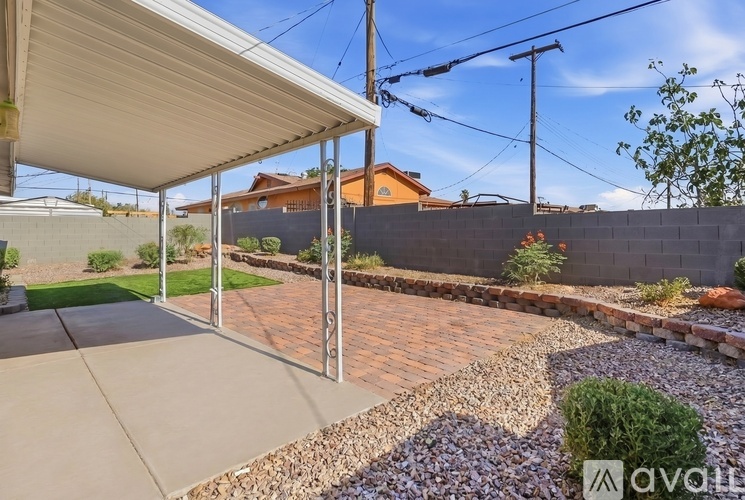 A patio area with a grey roof and a gravel garden bed.