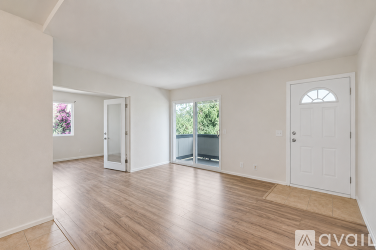 A spacious room with wooden flooring and white walls.