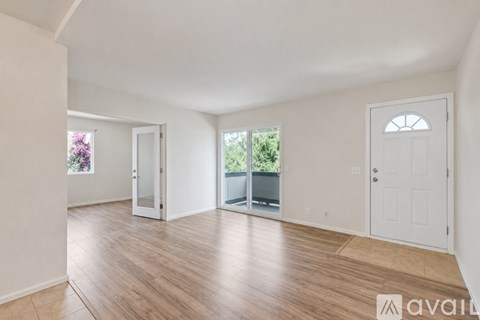 A spacious room with wooden flooring and white walls.