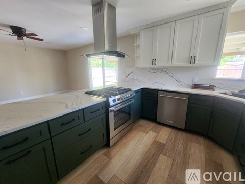 A kitchen with a stove top oven and a fan.