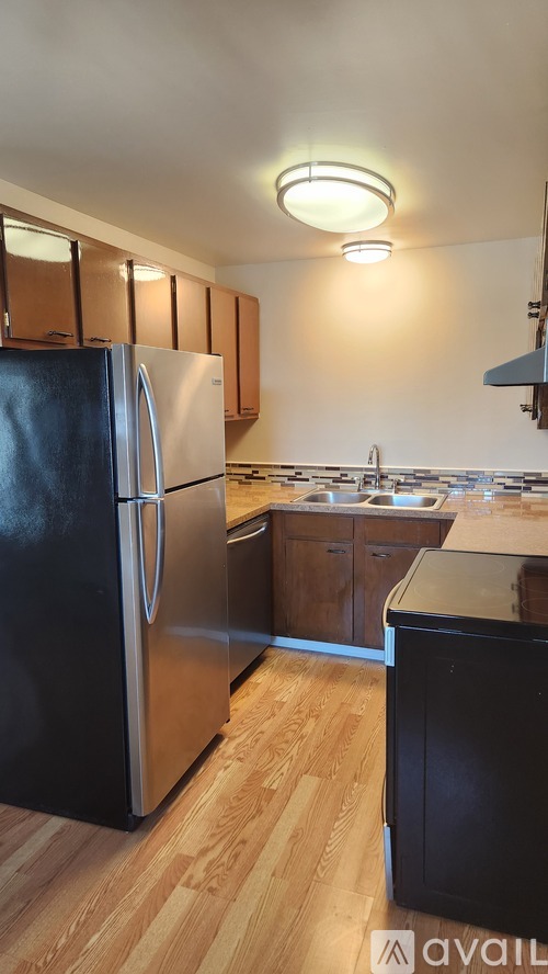 A kitchen with a black fridge and wooden floors.