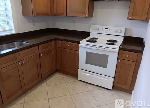 A white stove is in a kitchen with wooden cabinets.