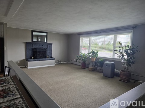 A living room with a fireplace and a rug on the floor.