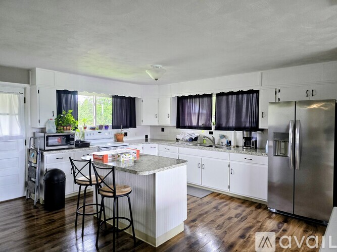 A kitchen with white cabinets and a wooden floor.