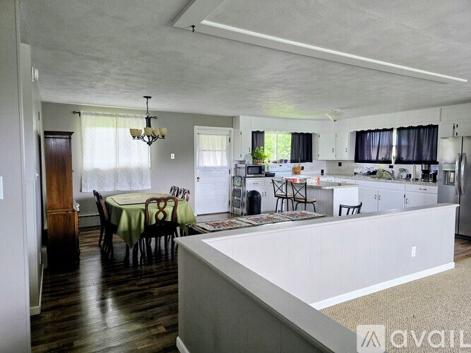 A large open plan kitchen and dining room with wooden floors and white walls.