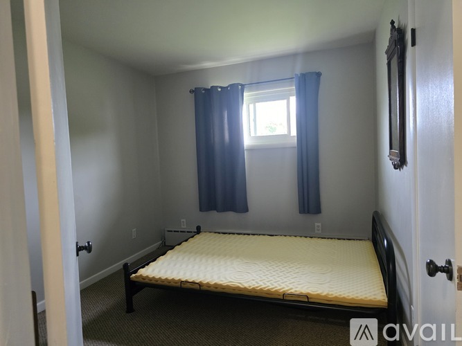 A small bedroom with a single bed and a window with blue curtains.