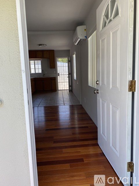 A hallway with a white door and wooden floors.