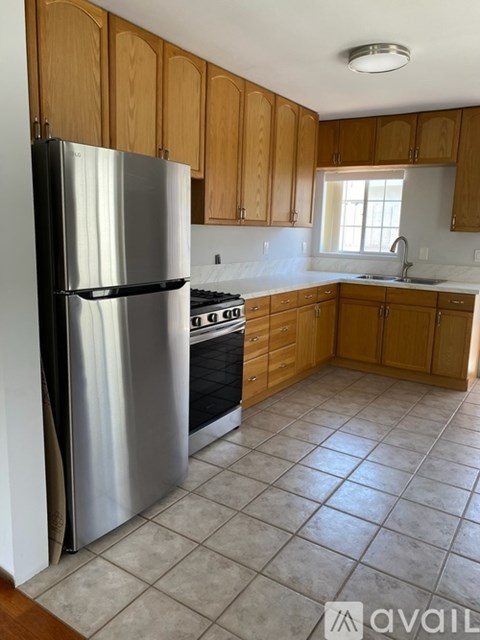A kitchen with wooden cabinets and a stainless steel refrigerator.