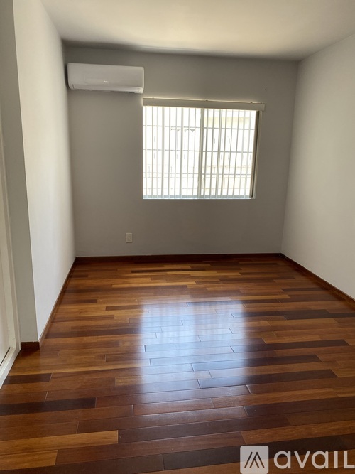 A room with wooden flooring and a window with blinds.