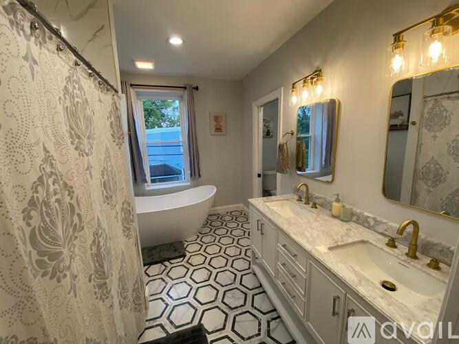 A bathroom with a white tub, sink, and hexagonal tile floor.