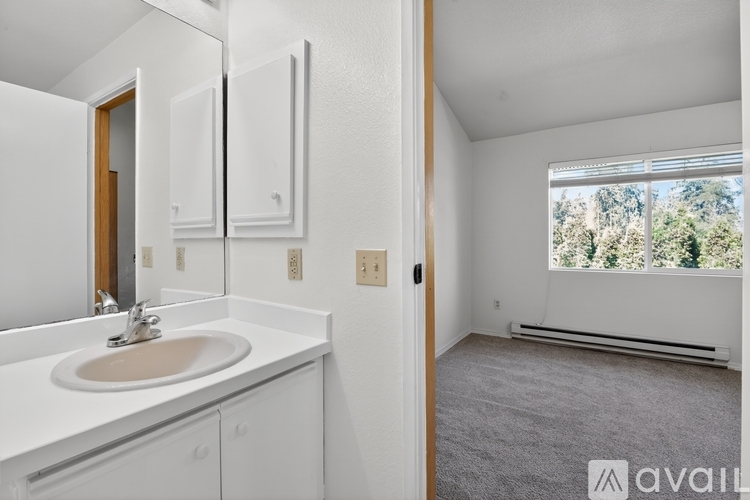 A bathroom with a sink, mirror, and a window with a view of trees outside.