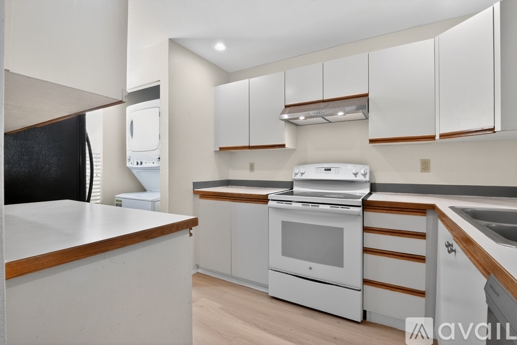 A modern kitchen with white cabinets and a wooden counter.