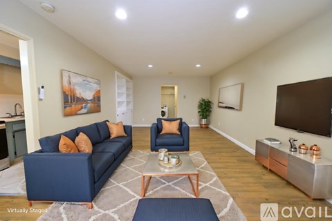 A living room with a blue couch and a painting on the wall.