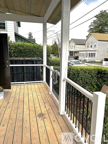 A wooden deck with a white railing and a black gate.