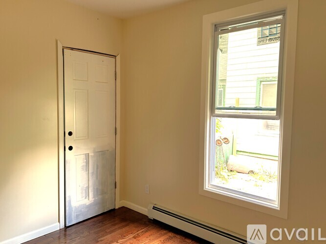 A room with a white door and a window showing a view of a building outside.