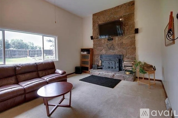 A living room with a fireplace and a brown leather couch.
