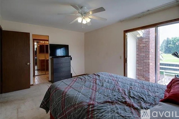 A bedroom with a bed, a ceiling fan, and a television.