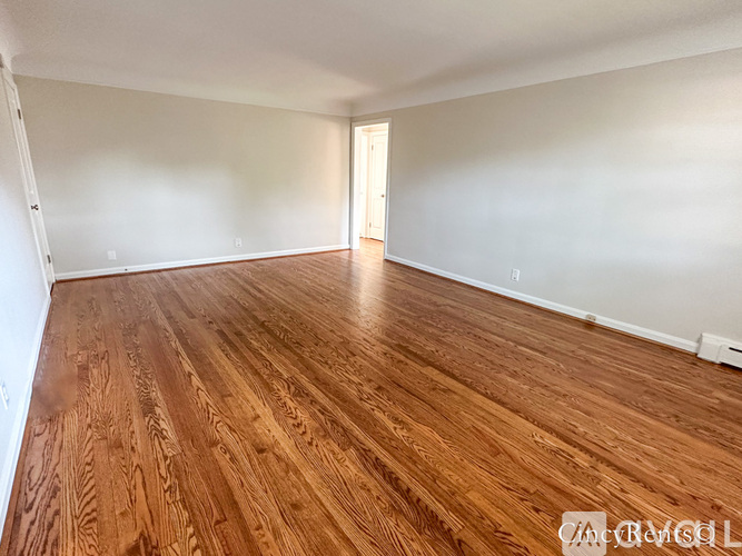 A room with wooden flooring and a doorway leading to another room.