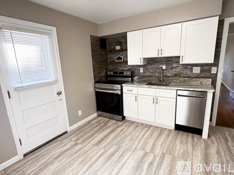 A kitchen with white cabinets and a stone backsplash.