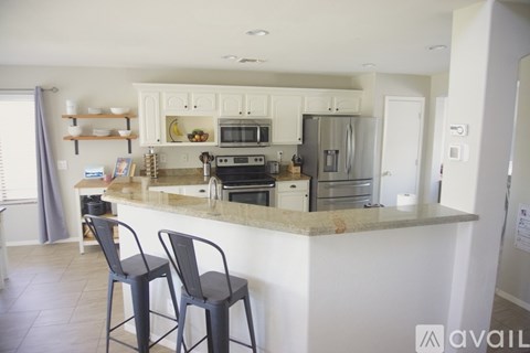 A kitchen with a marble countertop and black chairs.