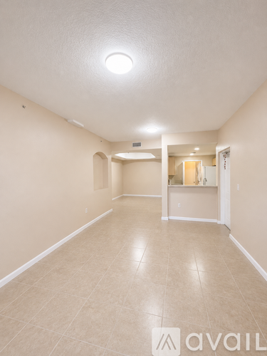 A spacious room with beige walls and floor, and a mirror on the wall.