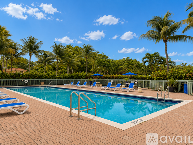 A pool surrounded by palm trees and lounge chairs.