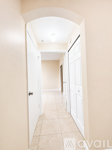 A hallway with white doors and tiled flooring.