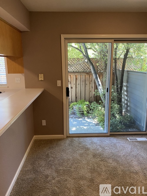 A room with a carpeted floor and a sliding glass door leading to a backyard.