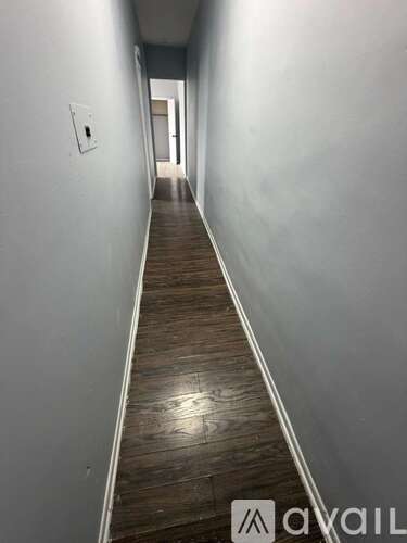 A long hallway with wood flooring and white walls.