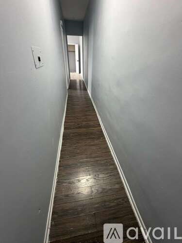 A long hallway with wood flooring and white walls.