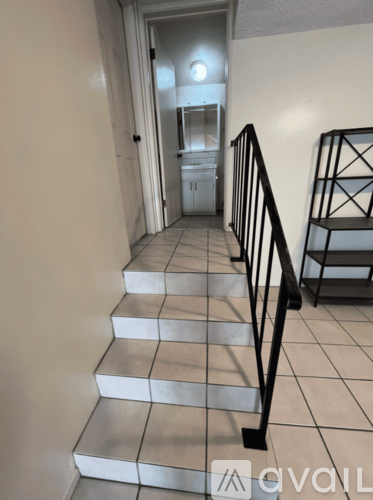 A hallway with a staircase and a mirror on the wall.