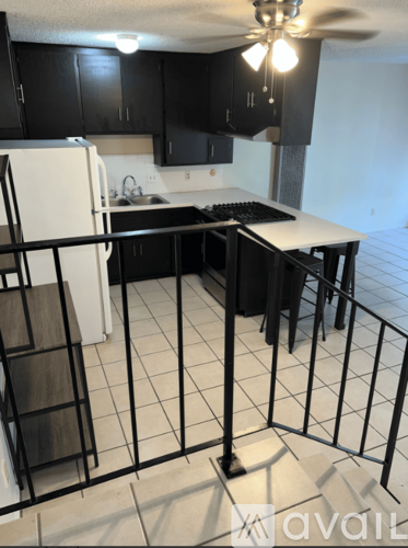 A kitchen with black cabinets and a white refrigerator.
