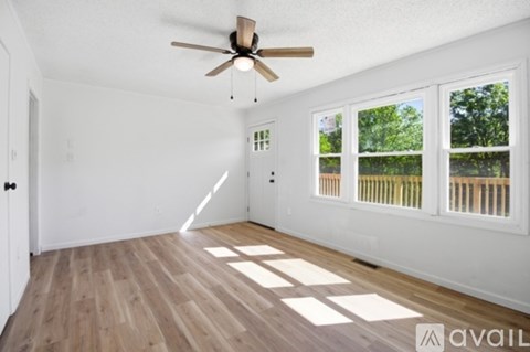 A room with a ceiling fan and wooden flooring.