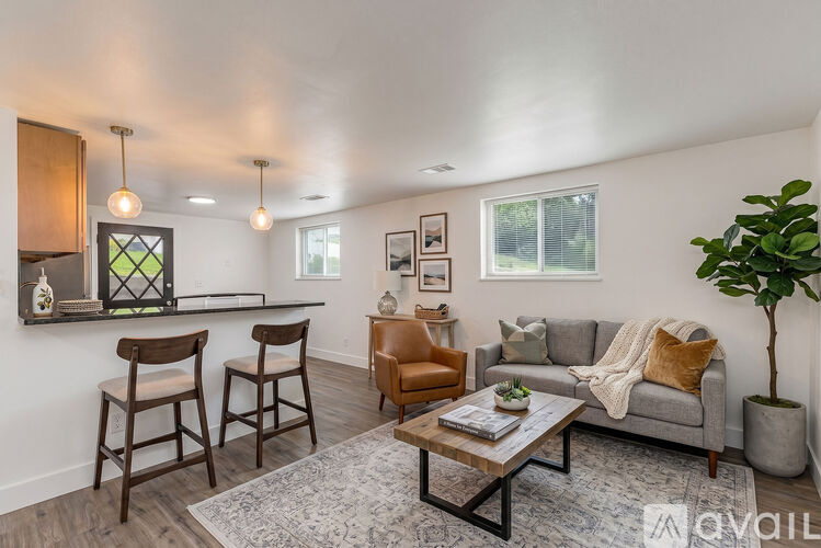 A living room with a grey couch, a coffee table, and a potted plant.