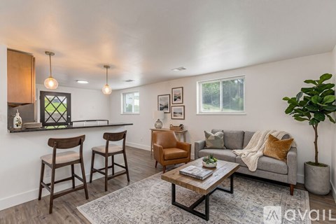 A living room with a grey couch, a coffee table, and a potted plant.