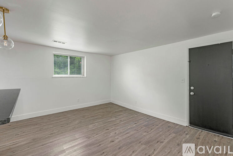 A room with wooden flooring and a window with a view of trees.