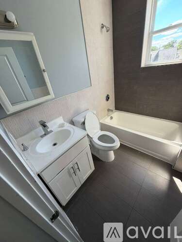 A bathroom with a toilet, sink, and mirror.