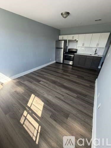 A kitchen with wood flooring and a white wall.