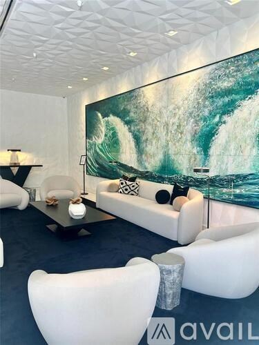 A modern living room with a large wave painting on the wall.
