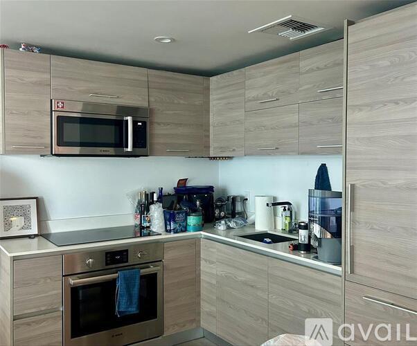 A modern kitchen with a microwave above the stove and a towel hanging in the oven.