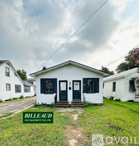 A white house with a green door and a sign that says "Billeaud Management Co. Inc." in front of it.