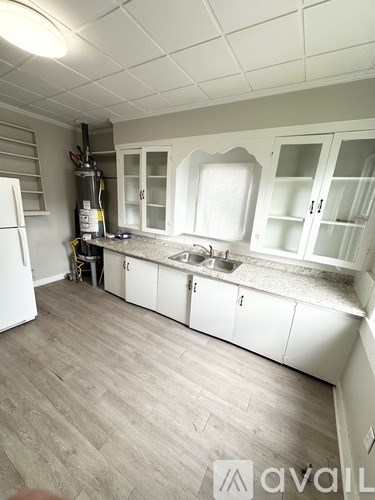 A kitchen with white cabinets and a wooden floor.