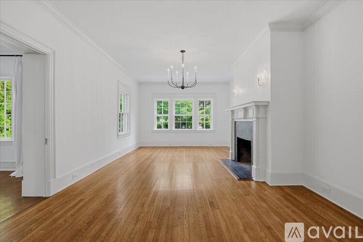 A spacious room with wooden floors and a fireplace.