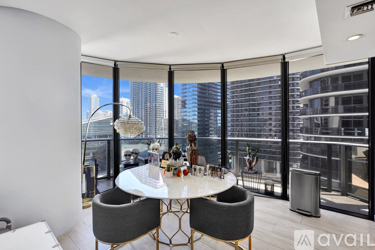 A modern dining room with a large table and chairs, a chandelier, and a view of the city.