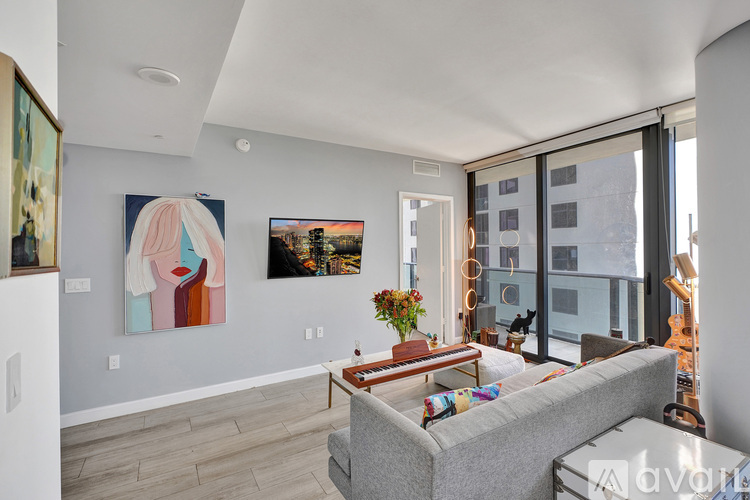 A living room with a grey couch and a painting on the wall.