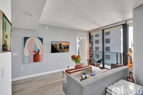 A living room with a grey couch and a painting on the wall.
