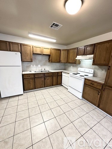 A kitchen with white appliances and brown cabinets.