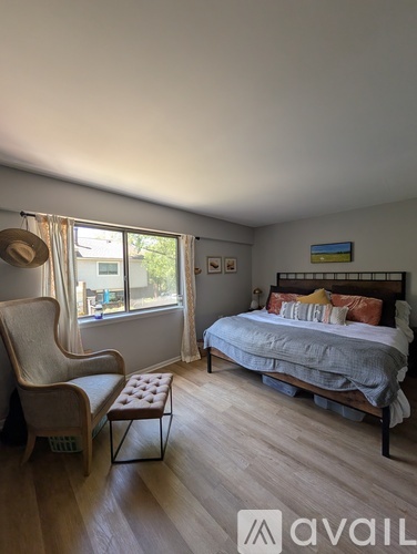 A bedroom with a bed, chair, and window.